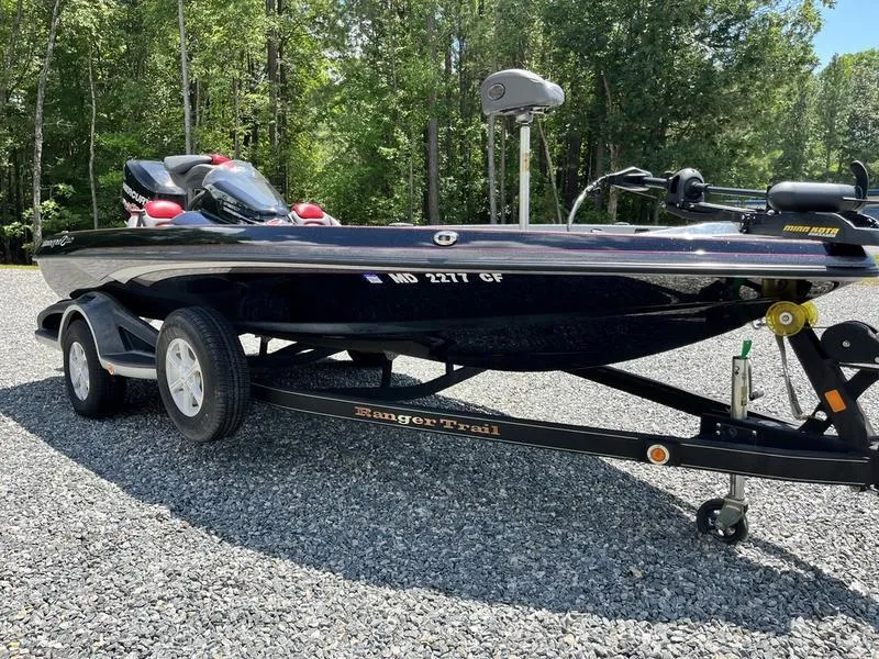 Slide: The Image of 2014 Ranger Z118 Comanche boat on trailer, parked on gravel, surrounded by trees. - 4