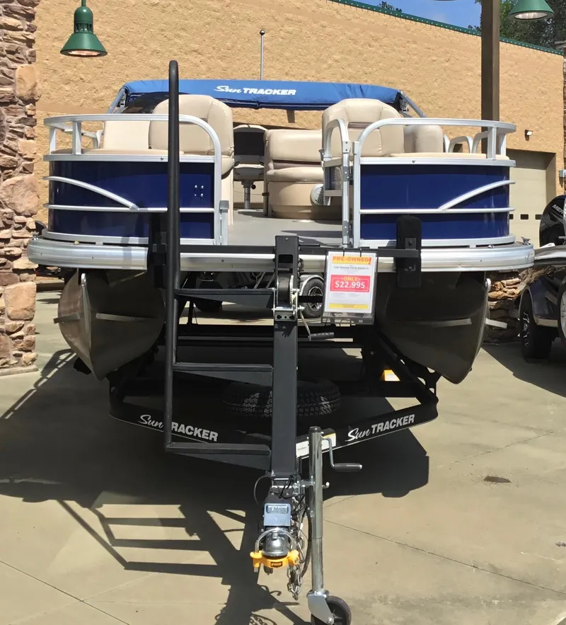Slide: The Image of 2017 Sun Tracker Fishin' Barge 22 DLX pontoon boat on trailer, displayed outdoors. - 4