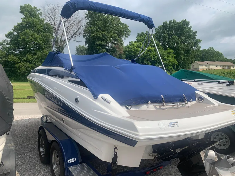 Slide: The Image of 2012 Crownline E1EC1Z boat with blue cover on trailer, parked outdoors. - 3