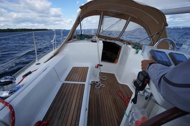 Slide: The Image of 2004 Jeanneau SO 37 sailboat cockpit with wooden deck and steering controls on open water. - 3