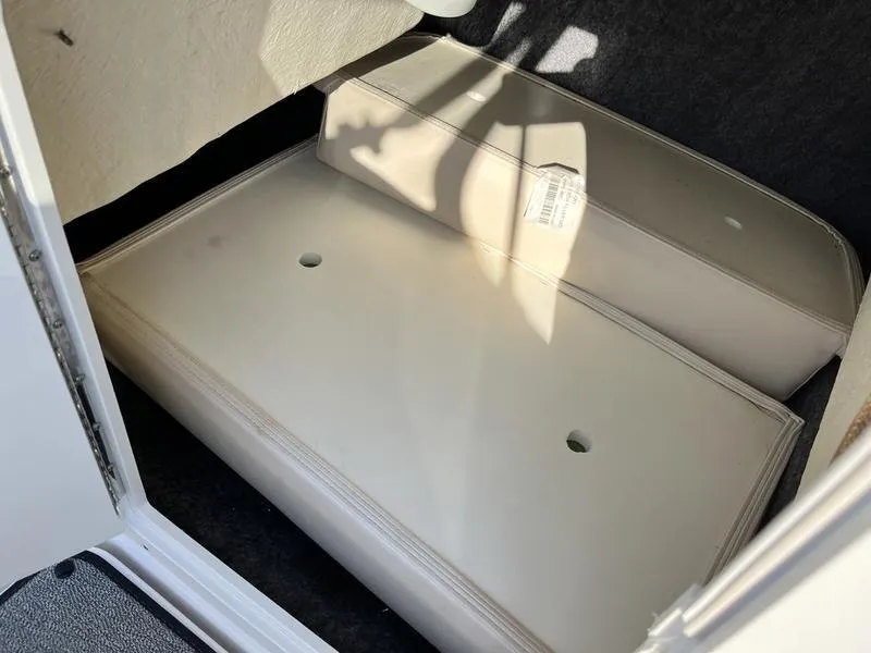 Slide: The Image of 2021 Yamaha AR195 boat storage compartment with cushioned seating and shadowed interior. - 11
