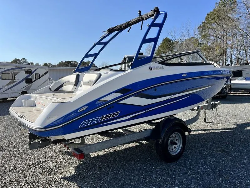 Slide: The Image of 2021 Yamaha AR195 boat on trailer, blue and white design, parked outdoors. - 3