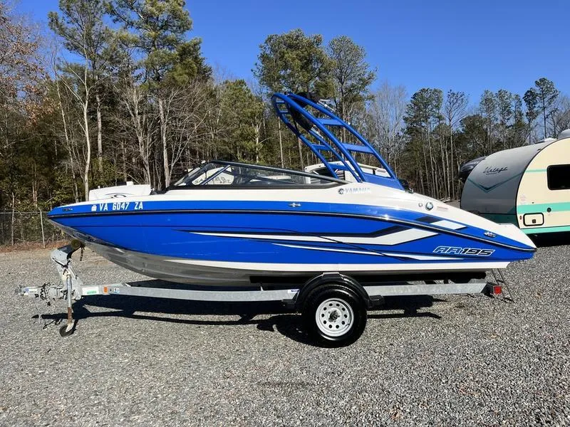 Slide: The Image of 2021 Yamaha AR195 boat in blue on a trailer, parked outdoors. - 8