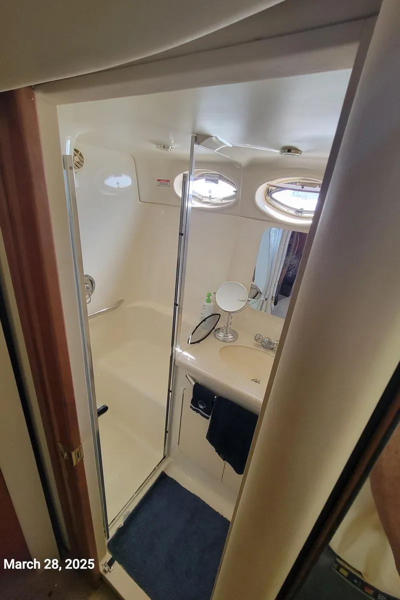 Slide: The Image of 2000 Sea Ray 380 Aft Cabin bathroom with shower, vanity, and porthole windows. - 38