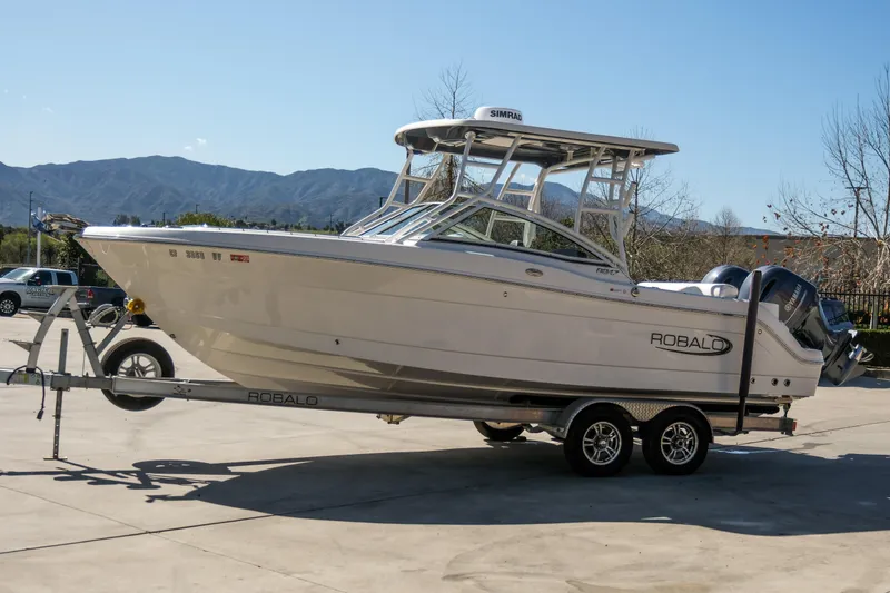 Slide: The Image of 2022 Robalo R247 Dual Console boat on trailer, parked outdoors. - 1
