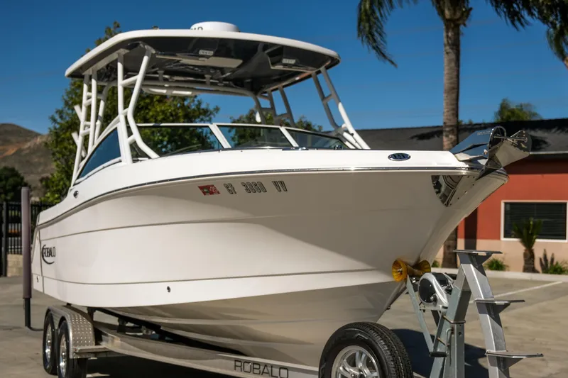 Slide: The Image of 2022 Robalo R247 Dual Console boat on trailer, parked outdoors under clear sky. - 15