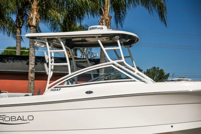 Slide: The Image of 2022 Robalo R247 Dual Console boat with T-top, parked near palm trees. - 17