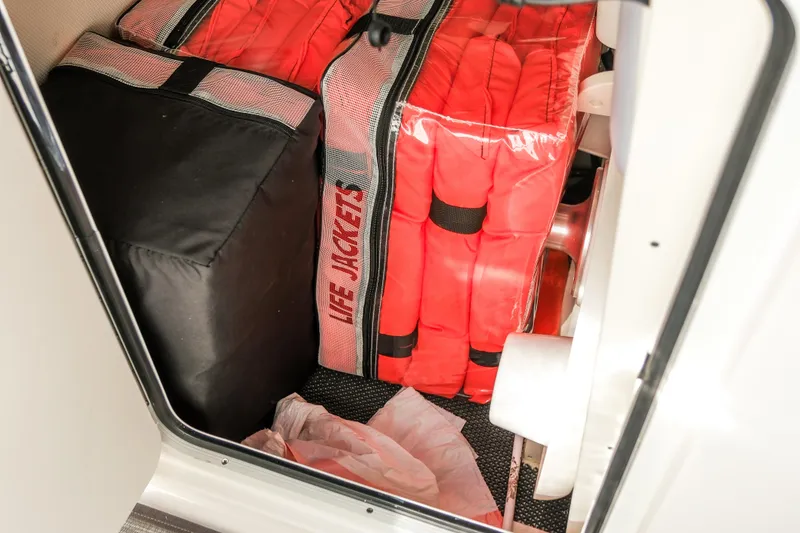 Slide: The Image of Storage compartment with life jackets on a 2022 Robalo R247 Dual Console boat. - 23
