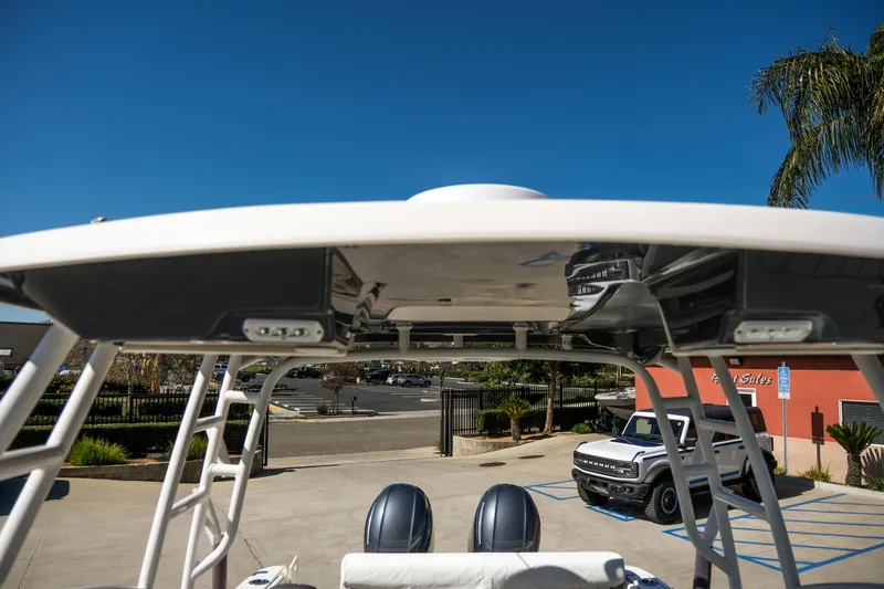 Slide: The Image of 2022 Robalo R247 Dual Console boat with T-top, parked outdoors under clear blue sky. - 7