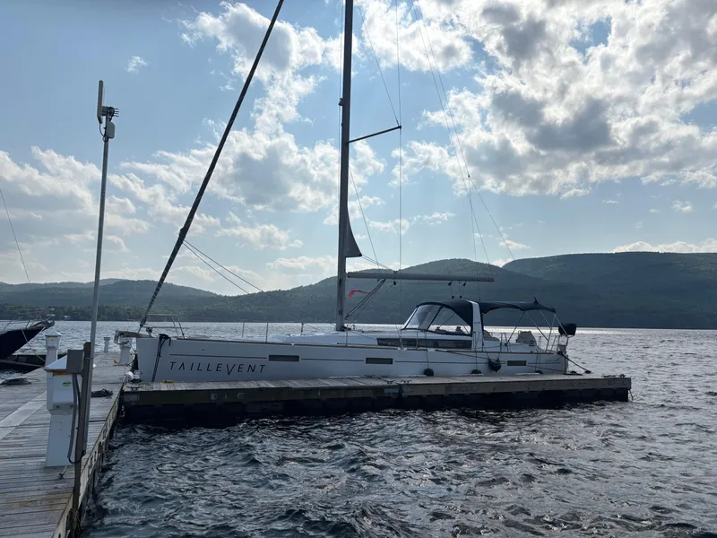 Slide: The Image of 2018 Beneteau Oceanis 45 sailboat docked on a sunny day with scenic mountain backdrop. - 1