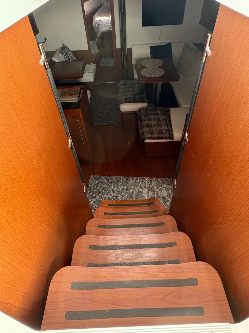 Slide: The Image of Interior view of 2018 Beneteau Oceanis 45 yacht, featuring wooden stairs and cozy seating area. - 13