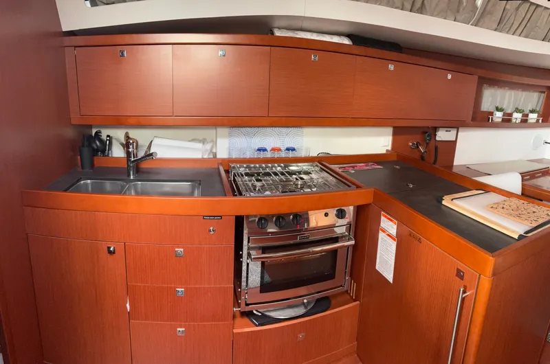 Slide: The Image of 2018 Beneteau Oceanis 45 yacht kitchen with wood cabinetry, stove, and sink. - 16