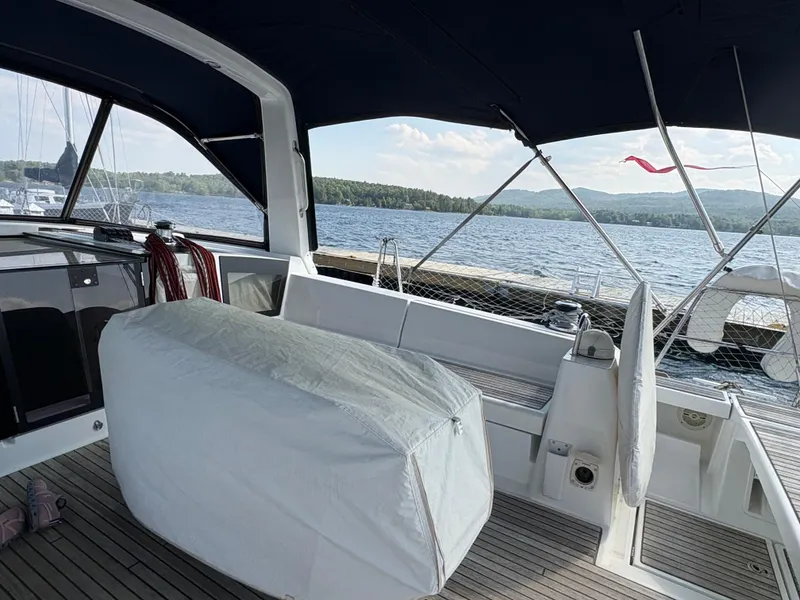 Slide: The Image of Beneteau Oceanis 45 yacht cockpit with covered seating, docked by a scenic lake, 2018 model. - 7