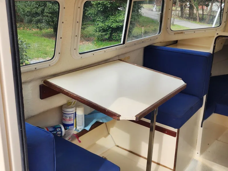Slide: The Image of 2006 C-Dory 22 Cruiser interior with blue seating and a foldable table. - 10