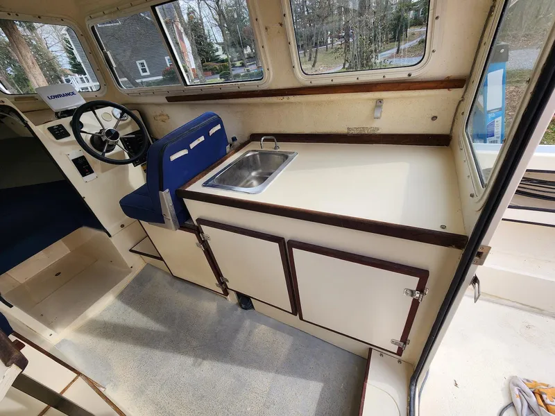 Slide: The Image of 2006 C-Dory 22 Cruiser interior with steering wheel, sink, and storage cabinets. - 12