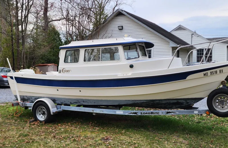 Slide: The Image of 2006 C-Dory 22 Cruiser boat on trailer, parked in front of a house. - 2