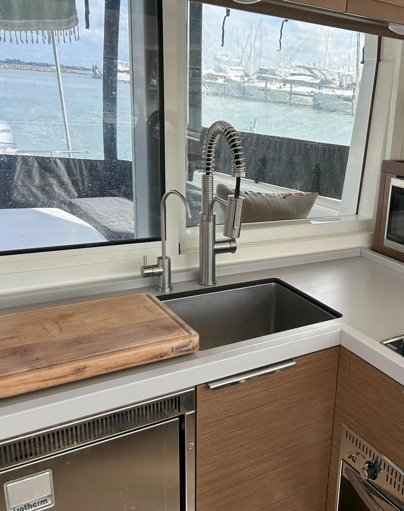 Slide: The Image of Modern kitchen in 2020 Lagoon 40 catamaran with ocean view, featuring sleek sink and wooden cabinetry. - 14