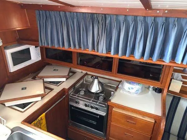 Slide: The Image of 1989 Custom SEA MAID boat kitchen with stove, microwave, and blue curtains. - 5