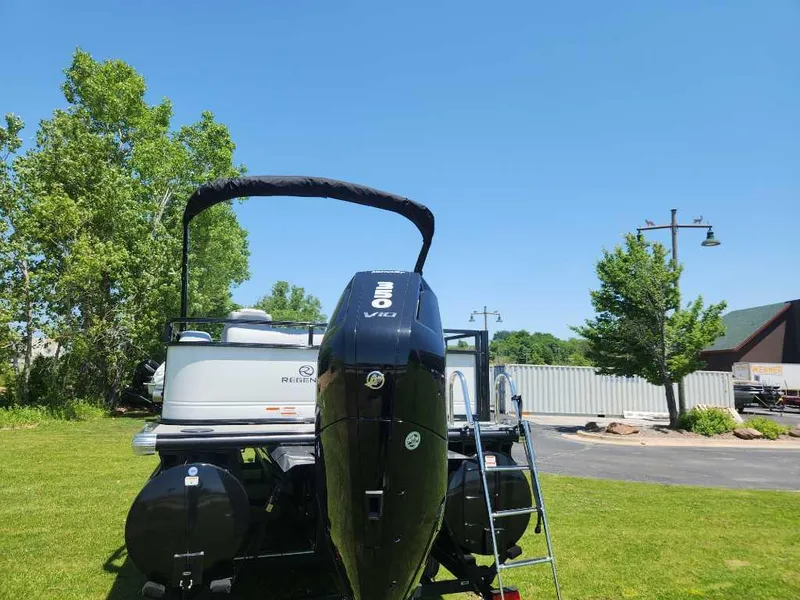 Slide: The Image of 2024 Regency 250 DL3 pontoon boat with outboard motor on grassy area. - 12