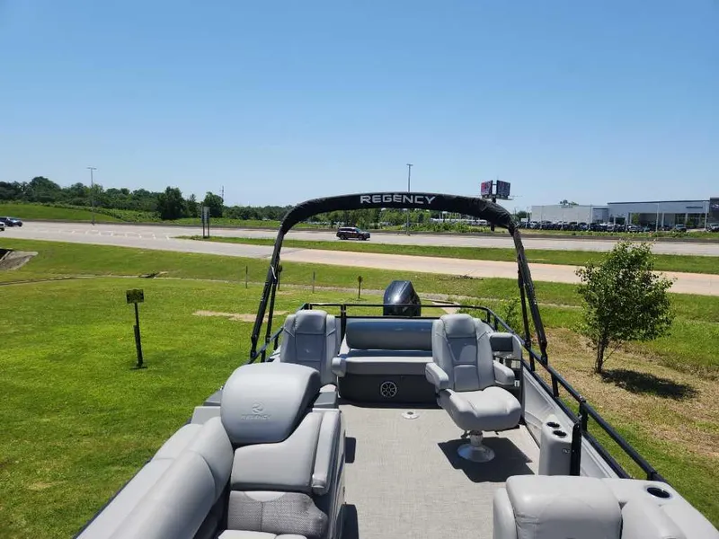 Slide: The Image of 2024 Regency 250 DL3 pontoon boat with spacious seating, parked on grassy area. - 19