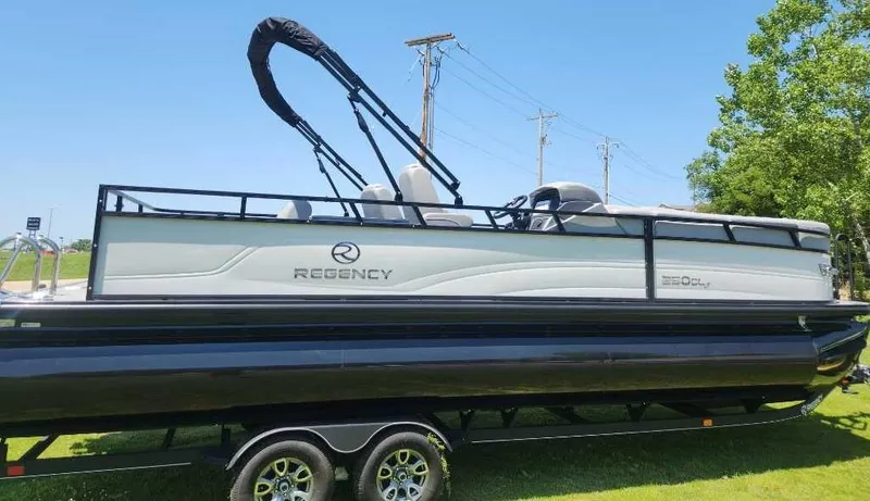 Slide: The Image of 2024 Regency 250 DL3 pontoon boat on trailer, side view, outdoors. - 4