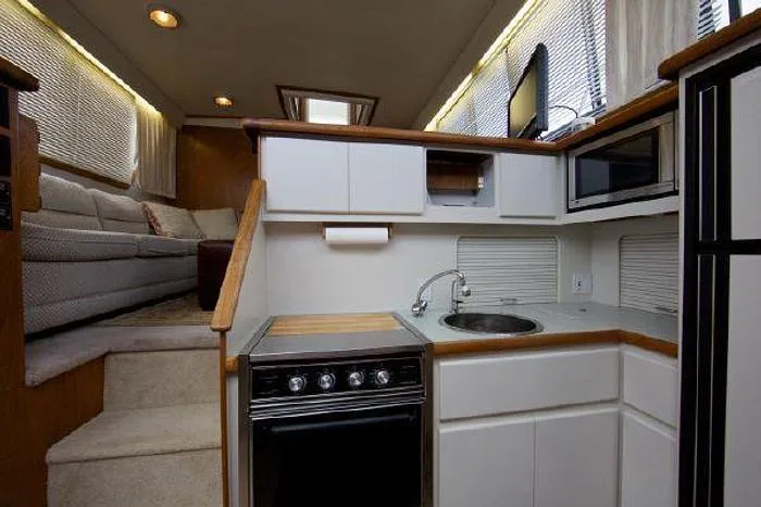 Slide: The Image of Interior of a 1994 Carver 390 yacht featuring a compact kitchen and cozy seating area. - 10