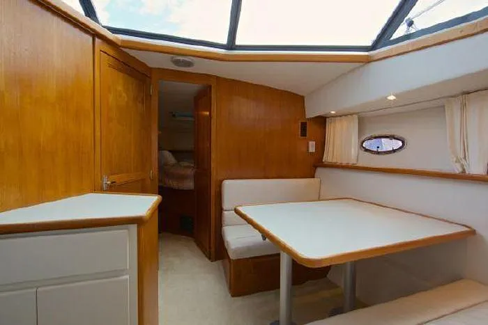 Slide: The Image of 1994 Carver 390 yacht interior with wooden cabinetry, dining area, and skylight. - 11