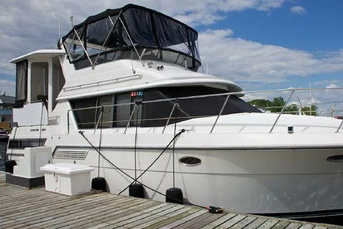 Slide: The Image of 1994 Carver 390 yacht docked at a marina under a partly cloudy sky. - 3