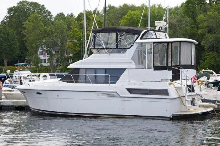 Slide: The Image of 1994 Carver 390 yacht docked in a marina, surrounded by lush greenery. - 4