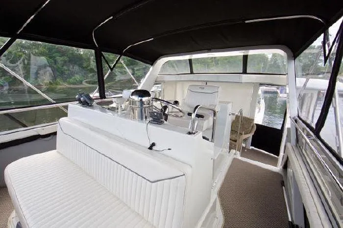 Slide: The Image of 1994 Carver 390 yacht interior with white seating and helm, under black canopy. - 6