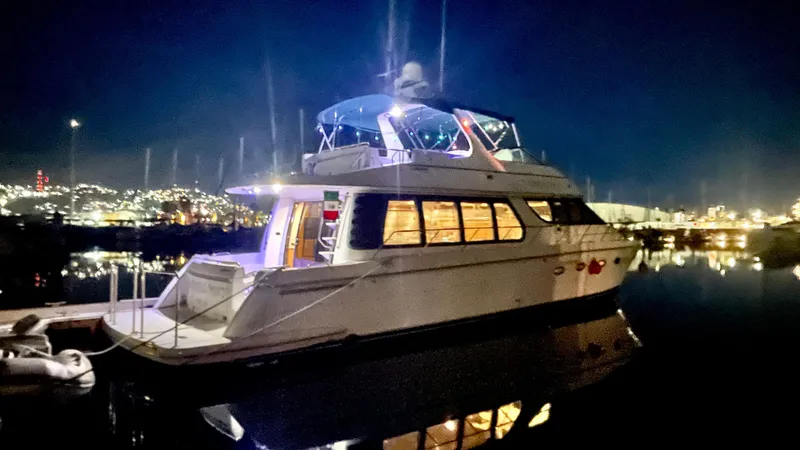 Slide: The Image of 2002 Carver 570 Voyager Pilothouse yacht illuminated at night, docked in a serene marina. - 3