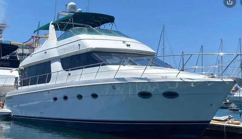 The Image of 2002 Carver 570 Voyager Pilothouse yacht docked in a marina under clear blue skies. - 0