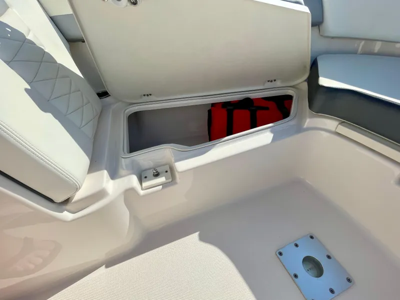 Slide: The Image of 2021 Robalo 247 Dual Console boat storage compartment with red life jacket inside. - 14