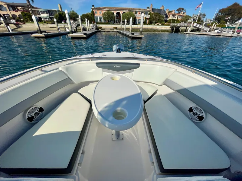 Slide: The Image of 2021 Robalo 247 Dual Console boat interior with seating and table, docked in a marina. - 15