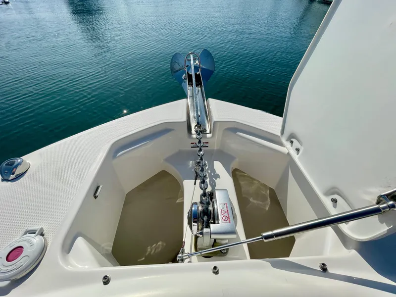 Slide: The Image of 2021 Robalo 247 Dual Console anchor compartment with chain and winch, docked on calm water. - 17