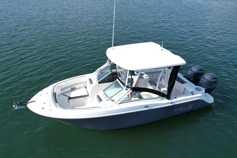 Slide: The Image of 2021 Robalo 247 Dual Console boat on calm water, featuring a sleek design and twin engines. - 2