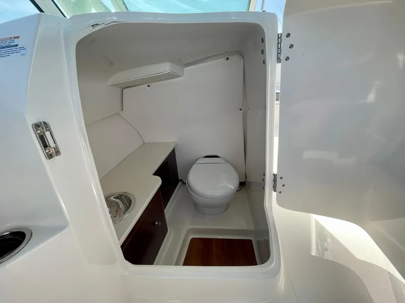 Slide: The Image of 2021 Robalo 247 Dual Console boat interior with compact bathroom and sink. - 20