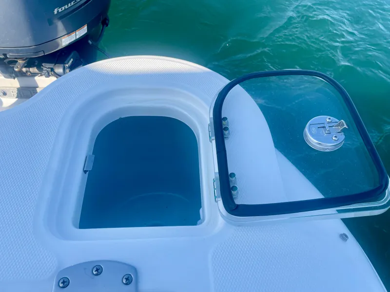 Slide: The Image of 2021 Robalo 247 Dual Console boat with open storage compartment near water. - 31