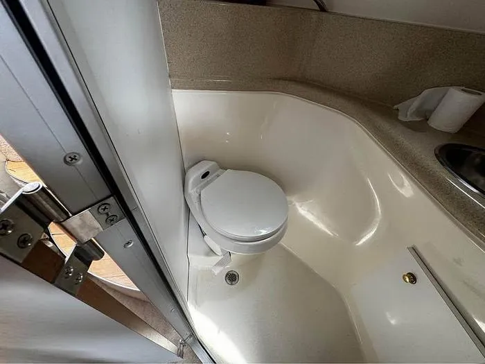 Slide: The Image of Compact bathroom in a 2000 Wellcraft 3200 boat, featuring a toilet and sink. - 19