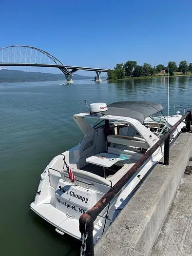 Slide: The Image of Wellcraft 3200 boat docked by a river with a bridge in the background, 2000 model. - 4