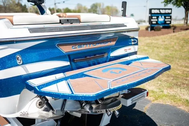 Slide: The Image of 2022 Centurion Ri265 boat rear view with blue and wood accents. - 13