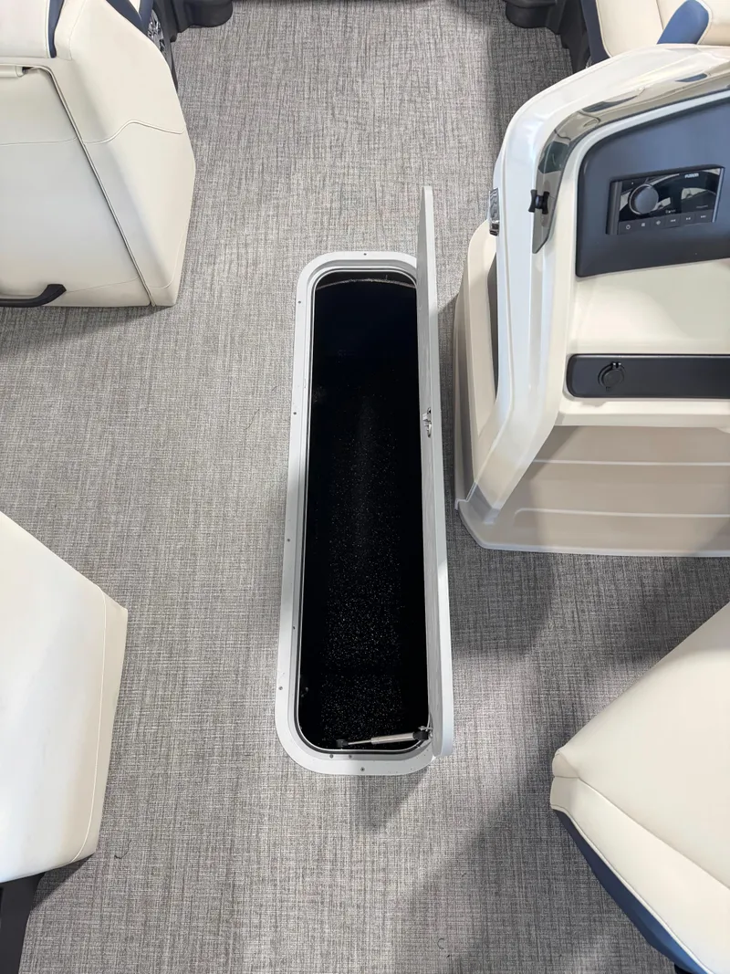 Slide: The Image of 2025 Tahoe Pontoon LTZ Versatile Rear Bench interior storage compartment, open on carpeted floor. - 6