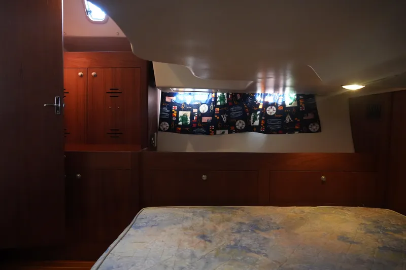 Slide: The Image of Cozy cabin interior of 1998 Hunter 410 sailboat with wooden cabinetry and nautical-themed curtains. - 37