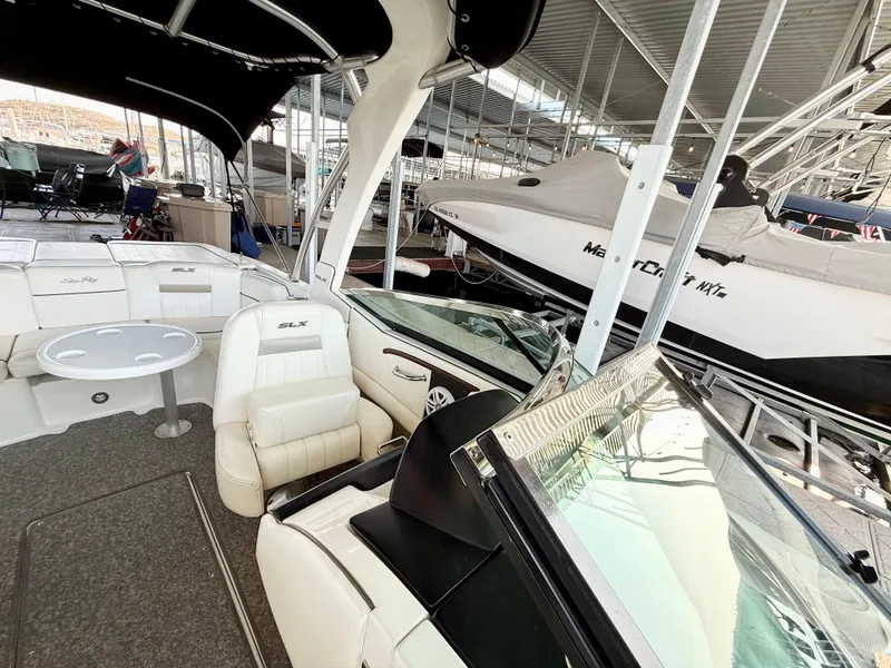 Slide: The Image of 2010 Sea Ray 250 SLX boat interior with white seating and table, docked in a marina. - 17