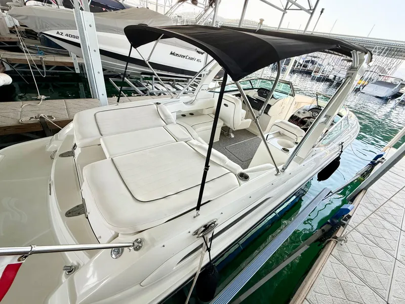 Slide: The Image of 2010 Sea Ray 250 SLX boat docked, featuring spacious seating and a black canopy. - 24
