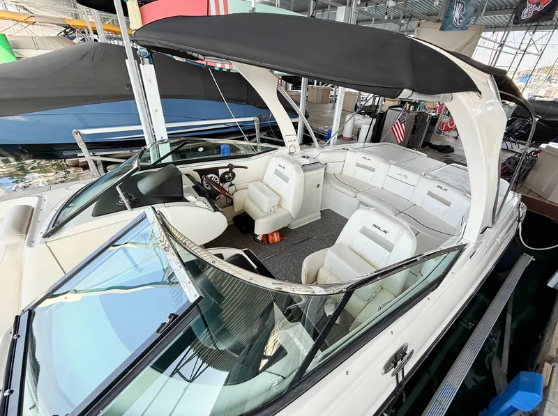 Slide: The Image of 2010 Sea Ray 250 SLX boat with black canopy and white seating in a marina. - 26