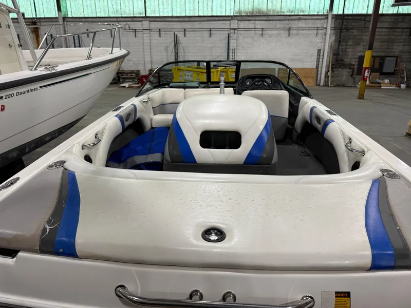 Slide: The Image of 2002 Malibu Response LX boat interior with white and blue seating in a warehouse. - 5