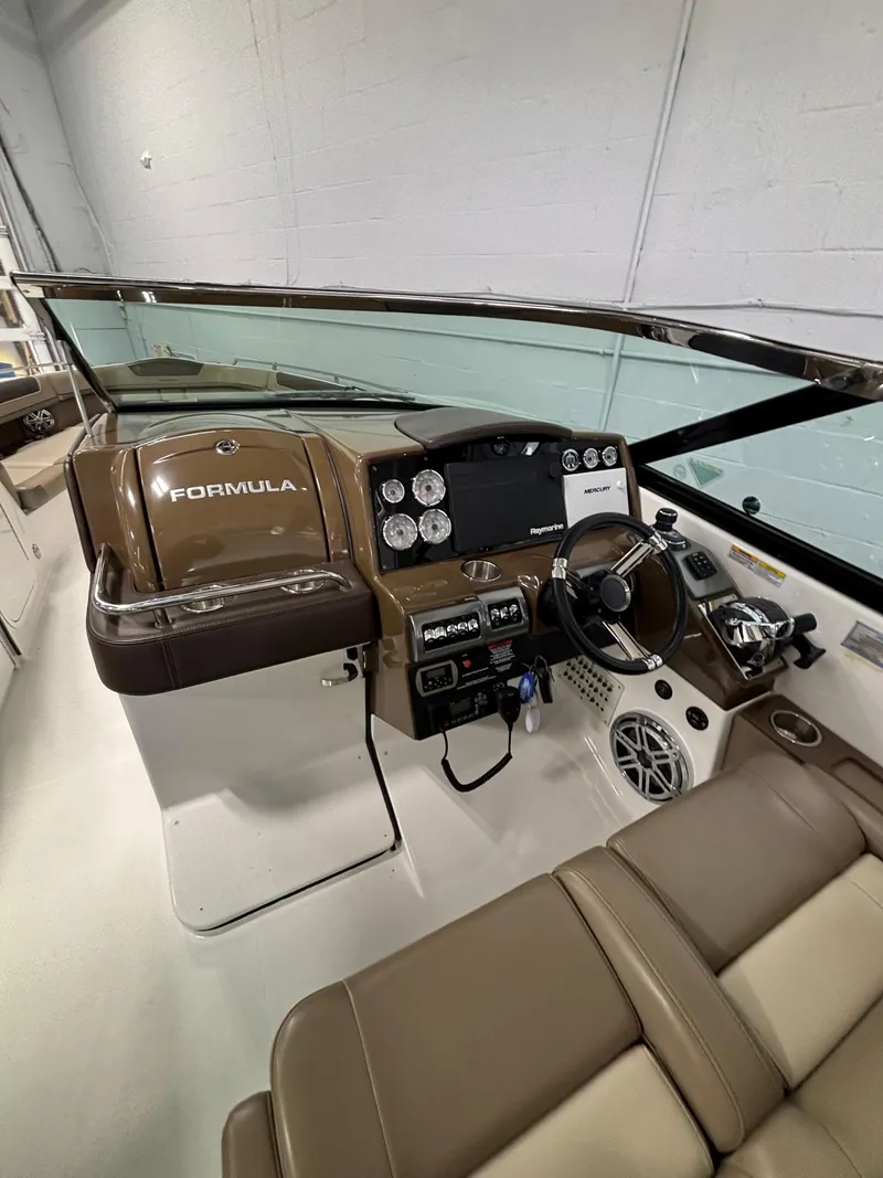 Slide: The Image of 2019 Formula 350 Crossover Bowrider I/O helm with modern controls and brown seating. - 7