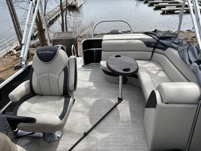 Slide: The Image of 2021 South Bay 200 Series S222CR pontoon boat interior with plush seating and table. - 11