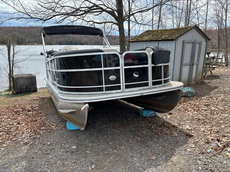 Slide: The Image of 2021 South Bay 200 Series S222CR pontoon boat on shore near a lake. - 6
